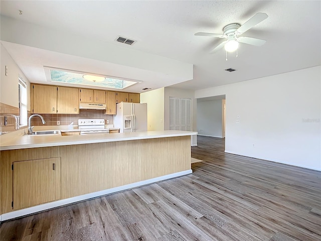 kitchen with kitchen peninsula, a skylight, white appliances, sink, and light hardwood / wood-style flooring