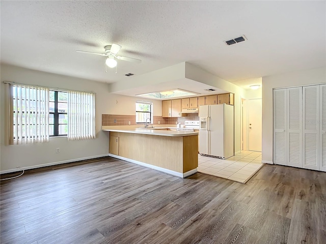 kitchen with ceiling fan, sink, light hardwood / wood-style flooring, kitchen peninsula, and white appliances