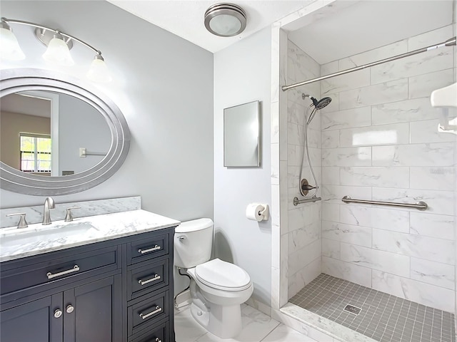 bathroom with tiled shower, vanity, and toilet