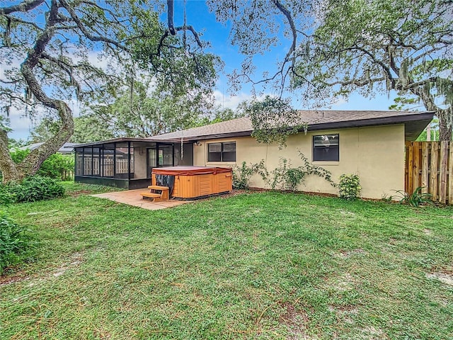 back of property with a yard, a hot tub, and a sunroom