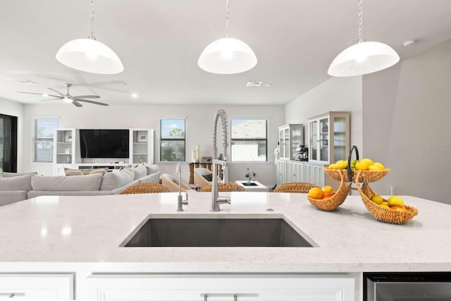 kitchen with light stone countertops, decorative light fixtures, and sink