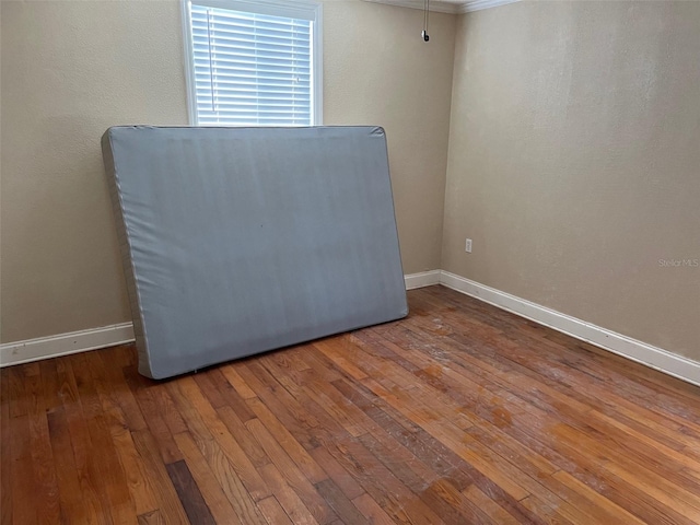 unfurnished room with hardwood / wood-style floors and crown molding