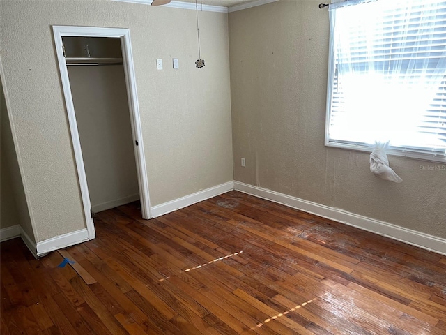 unfurnished bedroom featuring a closet, dark hardwood / wood-style floors, and ornamental molding