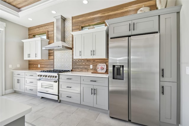 kitchen featuring backsplash, crown molding, stainless steel refrigerator with ice dispenser, wall chimney exhaust hood, and range with gas cooktop