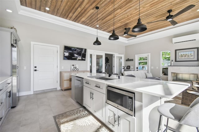 kitchen featuring stainless steel appliances, wooden ceiling, a raised ceiling, a wall mounted AC, and an island with sink