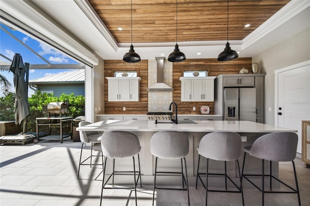 kitchen featuring white cabinets, stainless steel fridge, wall chimney exhaust hood, and sink