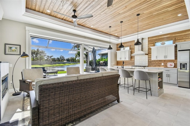 interior space with a raised ceiling, white cabinetry, stainless steel appliances, and wooden ceiling