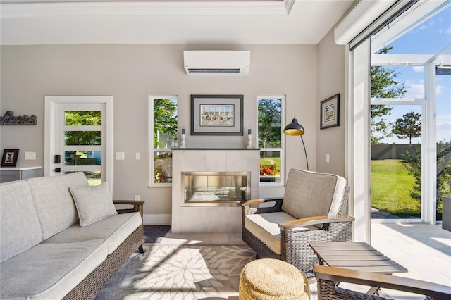 living room with a healthy amount of sunlight, crown molding, a wall unit AC, and a tiled fireplace