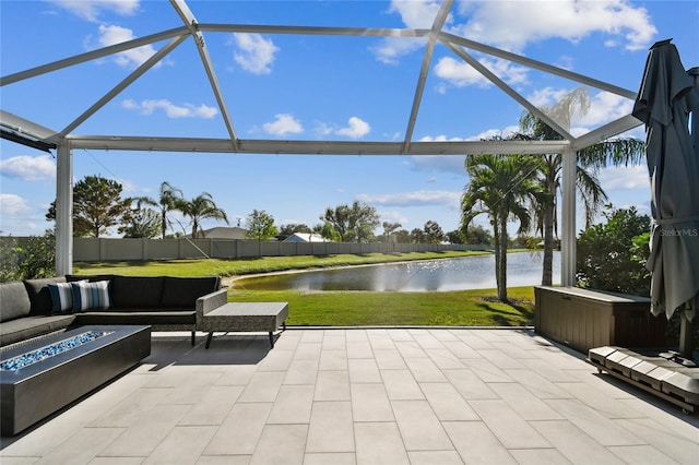 view of patio featuring glass enclosure, a water view, and an outdoor living space with a fire pit