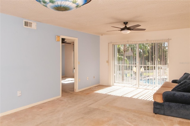 living room with a textured ceiling, light colored carpet, and ceiling fan