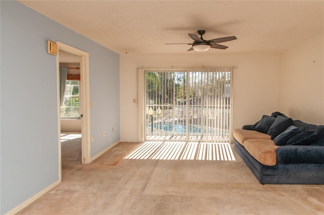 living room with ceiling fan, light colored carpet, and a textured ceiling