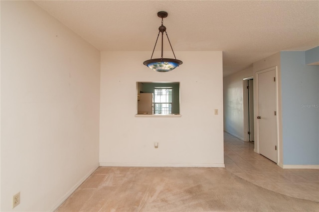 spare room with light carpet and a textured ceiling