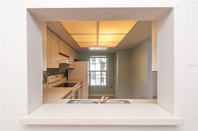 kitchen with white appliances, sink, tasteful backsplash, cream cabinetry, and kitchen peninsula