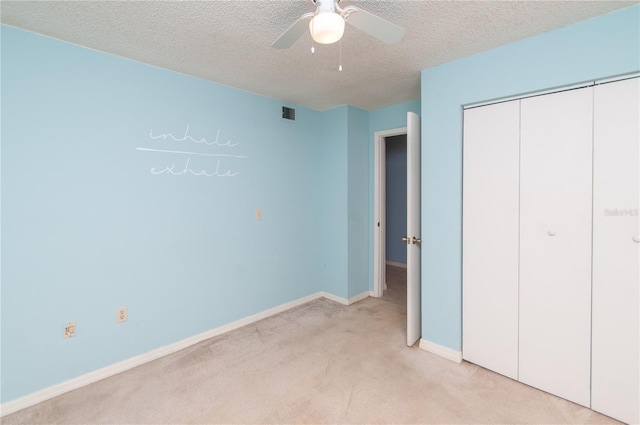 unfurnished bedroom with a textured ceiling, a closet, ceiling fan, and light colored carpet