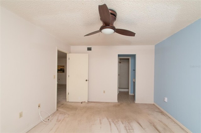 unfurnished bedroom with a textured ceiling, light colored carpet, ceiling fan, and connected bathroom