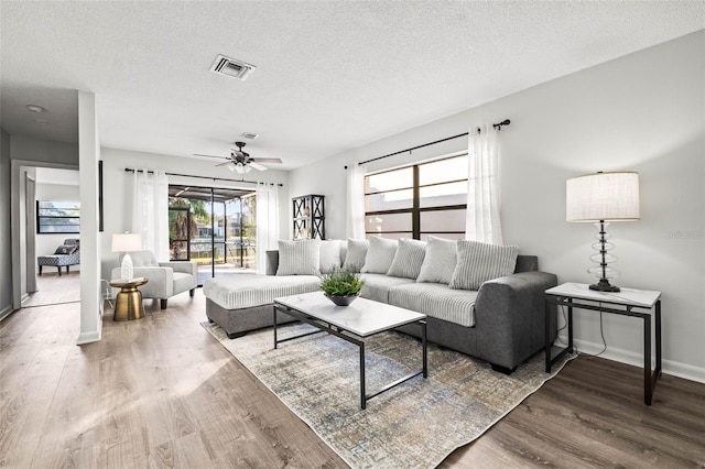 living room with wood-type flooring, ceiling fan, and a textured ceiling