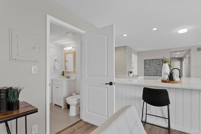 bathroom featuring electric panel, hardwood / wood-style floors, vanity, and toilet