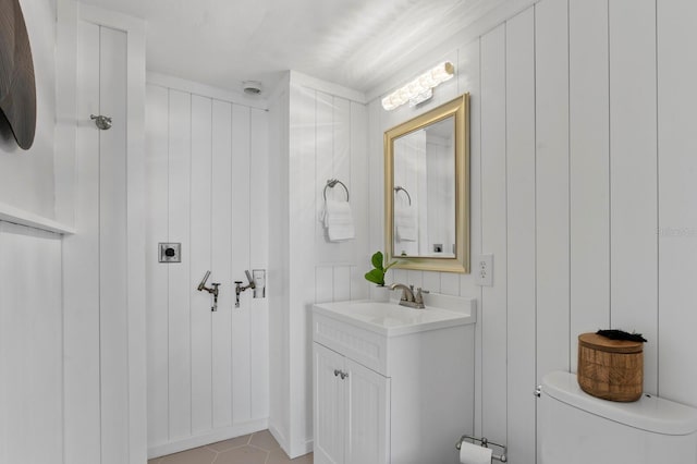 bathroom with tile patterned flooring, vanity, toilet, and wood walls