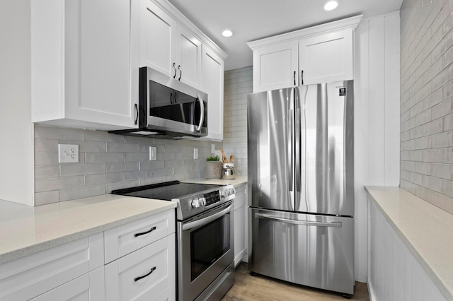 kitchen featuring light stone countertops, appliances with stainless steel finishes, backsplash, light hardwood / wood-style floors, and white cabinetry