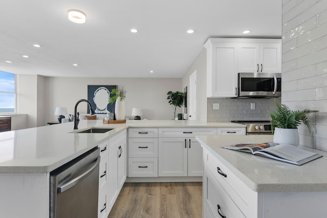 kitchen with sink, stainless steel appliances, light hardwood / wood-style floors, decorative backsplash, and white cabinets