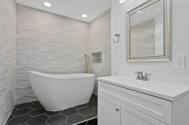 bathroom with a bath, vanity, tile patterned floors, and tile walls