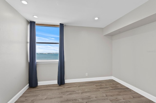 spare room featuring a water view and wood-type flooring