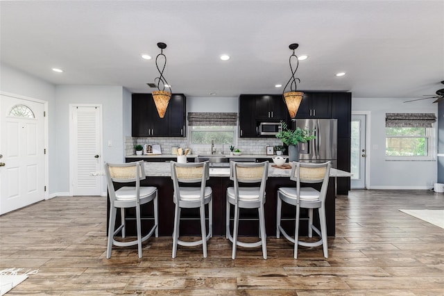 kitchen featuring stainless steel appliances, a kitchen island, a breakfast bar, and decorative light fixtures