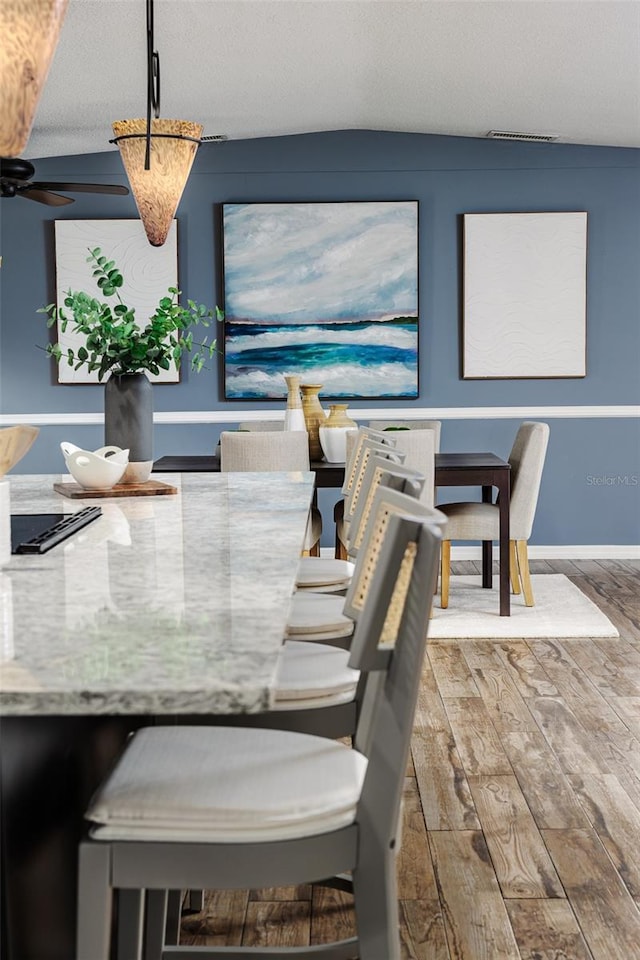 dining room featuring wood-type flooring, a textured ceiling, and ceiling fan