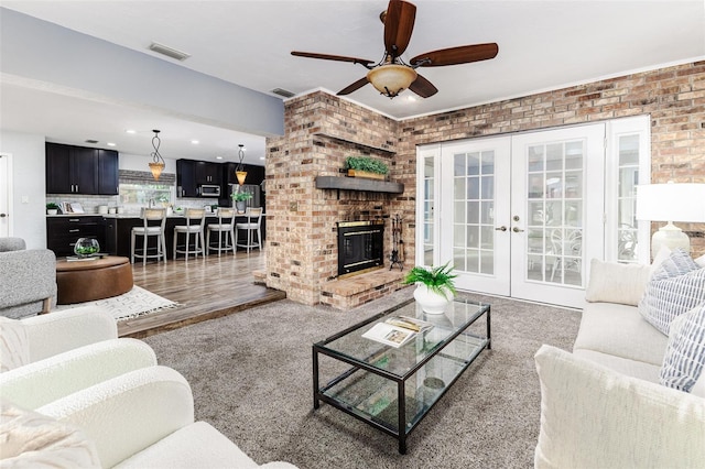 living room with french doors, ceiling fan, brick wall, and a fireplace