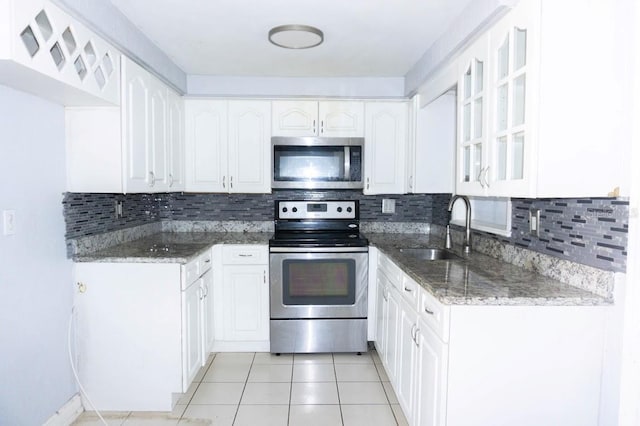 kitchen with appliances with stainless steel finishes, tasteful backsplash, white cabinetry, and dark stone counters