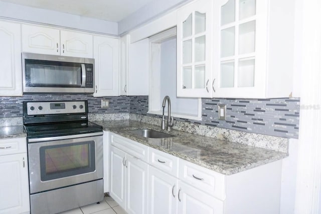 kitchen featuring backsplash, white cabinets, sink, light tile patterned floors, and stainless steel appliances