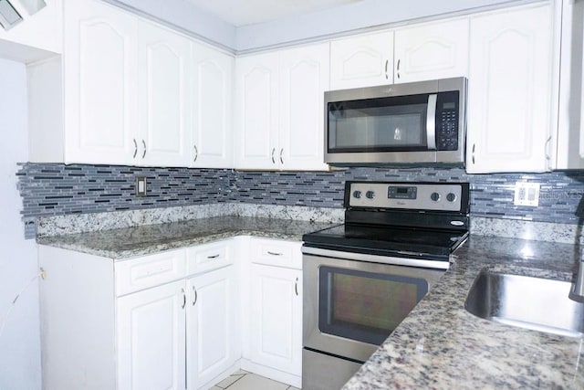 kitchen with white cabinetry, sink, backsplash, stone countertops, and appliances with stainless steel finishes