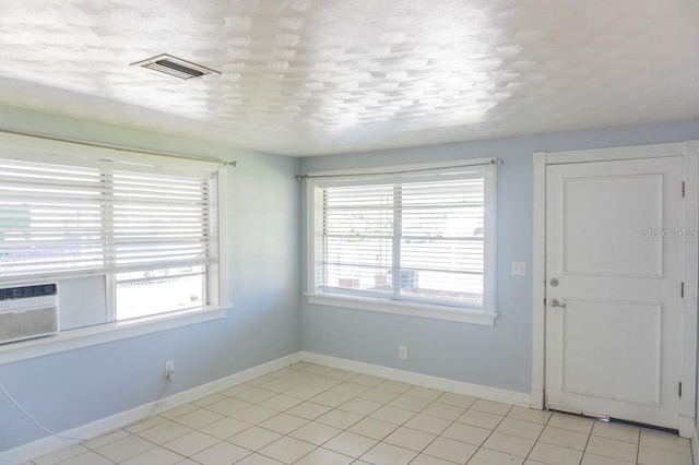 tiled spare room featuring cooling unit, a textured ceiling, and a wealth of natural light