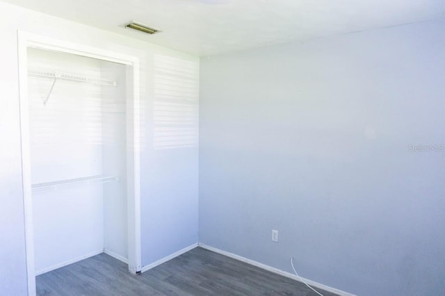 unfurnished bedroom with a closet and dark hardwood / wood-style floors