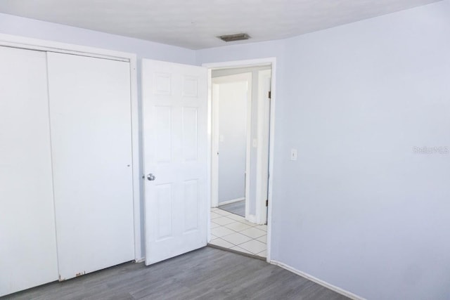 unfurnished bedroom with light wood-type flooring and a closet