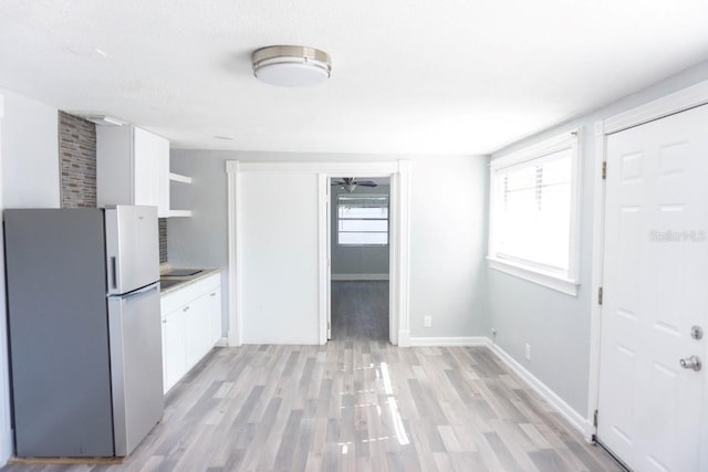 kitchen with light hardwood / wood-style floors, stainless steel refrigerator, white cabinetry, and ceiling fan