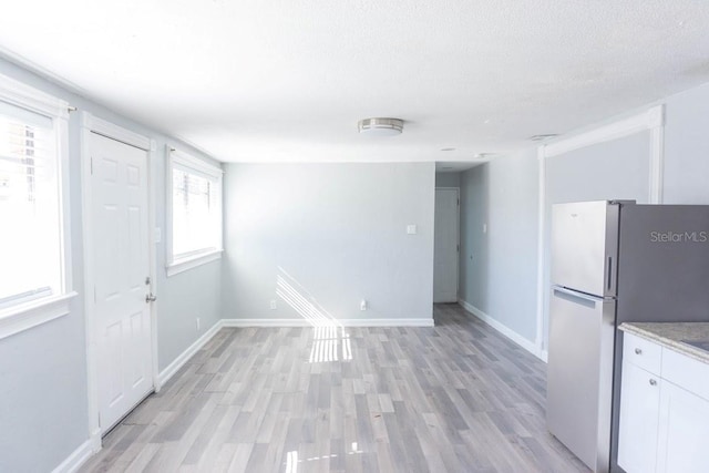 kitchen featuring white cabinets, light hardwood / wood-style floors, a textured ceiling, and stainless steel refrigerator