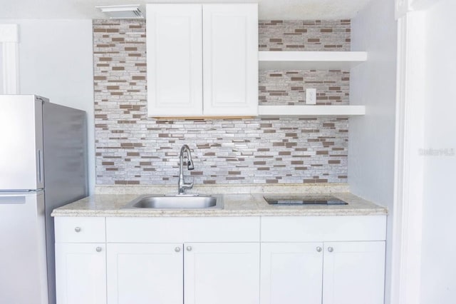 kitchen featuring white cabinets, decorative backsplash, stainless steel fridge, and sink