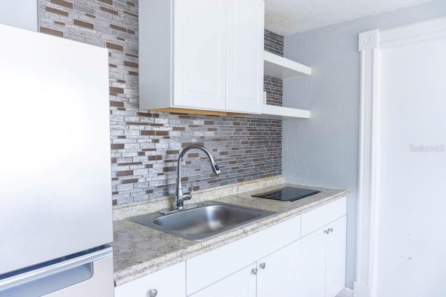 kitchen featuring decorative backsplash, a textured ceiling, sink, white refrigerator, and white cabinetry