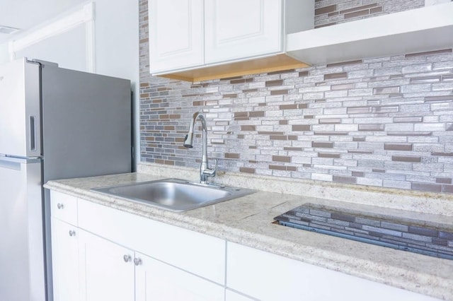 kitchen with decorative backsplash, stainless steel fridge, white cabinetry, and sink