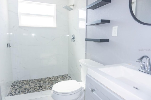 bathroom with tiled shower, vanity, and toilet