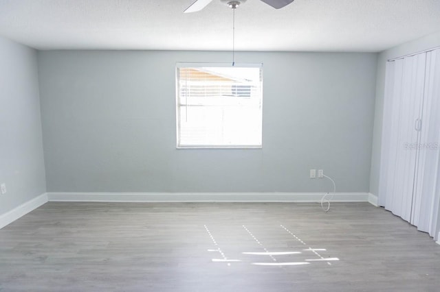 empty room with ceiling fan, light hardwood / wood-style floors, and a textured ceiling