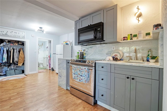 kitchen with decorative backsplash, light wood-type flooring, gray cabinetry, electric stove, and sink