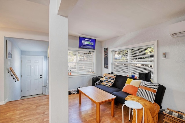 living room with a wall mounted air conditioner, a healthy amount of sunlight, and light hardwood / wood-style floors