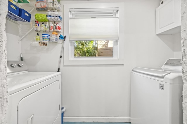 laundry room with separate washer and dryer and cabinets