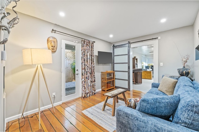 living room featuring a barn door, wood-type flooring, and a wealth of natural light