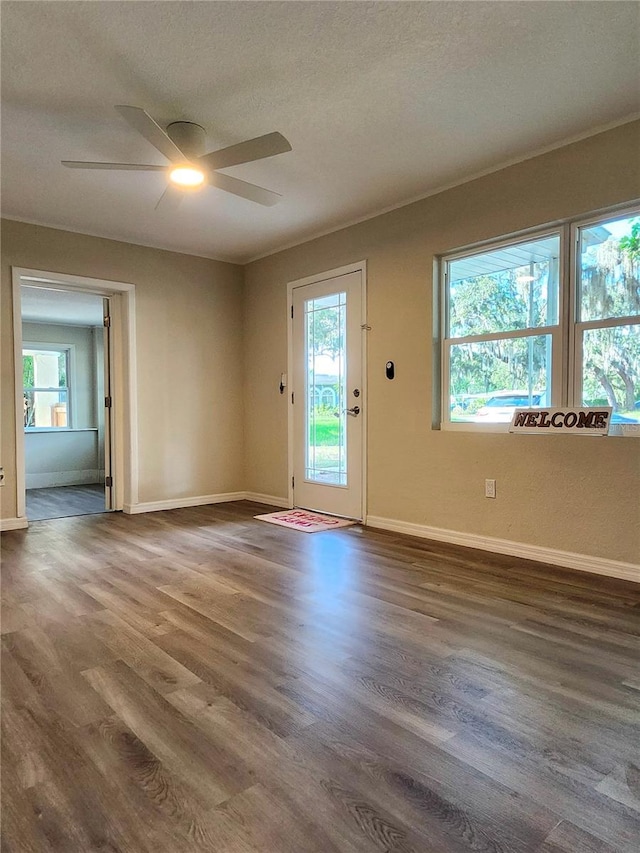 empty room with a textured ceiling, ceiling fan, and dark hardwood / wood-style floors