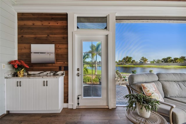 entryway featuring wood walls, a water view, and dark wood-type flooring