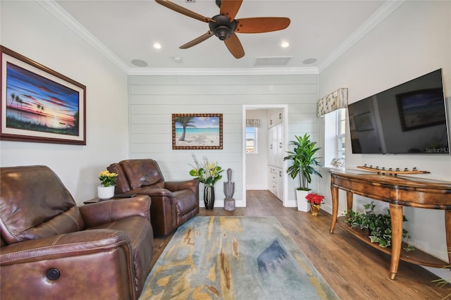 living room with wooden walls, crown molding, ceiling fan, and dark wood-type flooring