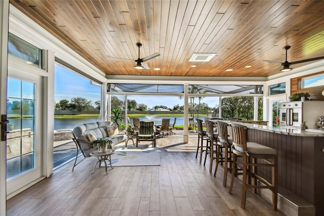 sunroom featuring a water view and wooden ceiling